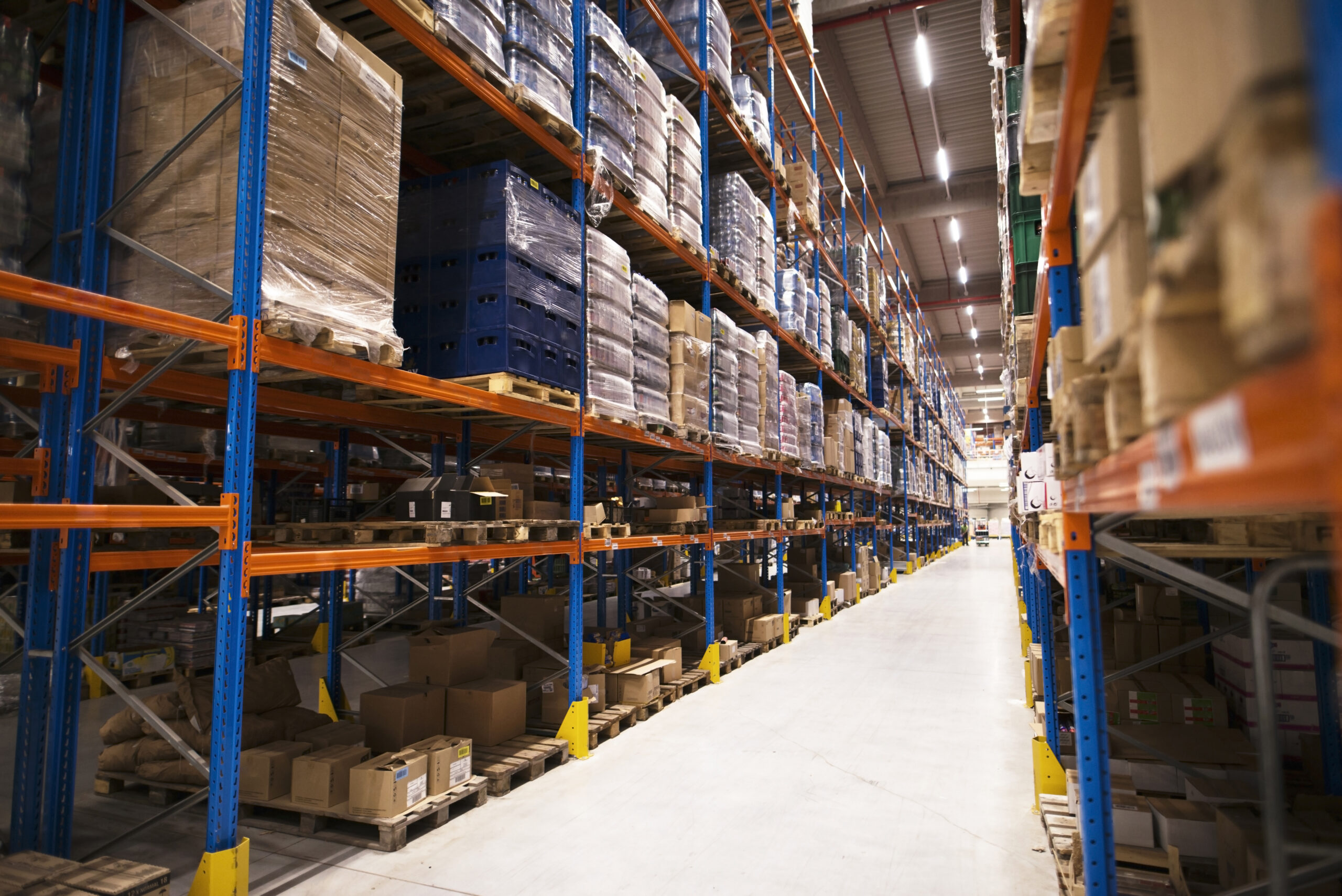 interior-large-distribution-warehouse-with-shelves-stacked-with-palettes-goods-ready-market-scaled